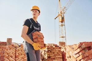 installation d'un mur de briques. ouvrier du bâtiment en uniforme et équipement de sécurité a un travail sur le bâtiment photo