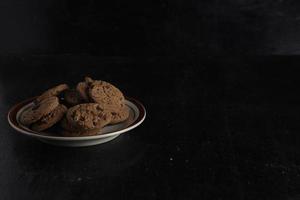 Cookies aux pépites de chocolat sur la plaque sur fond noir photo