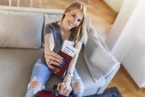 la femme se prépare à voyager pendant la pandémie de covid-19. tenant un passeport, un billet et un test de coronavirus négatif en main pendant que la valise se tient à proximité. concept de voyage et de vacances d'été photo