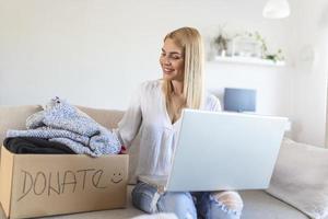 femme tenant une boîte de dons en carton pleine de vêtements. concept de travail bénévole, de don et de recyclage de vêtements. aider les pauvres photo