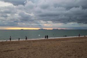 voyage sur l'île de koh lanta, en thaïlande. la vue sur la plage de sable avec des promeneurs au coucher du soleil. photo