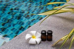 bouteilles d'huile essentielle d'arôme et de fleur de frangipanier sur le fond de la piscine pour le thème du spa. photo