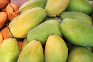 voyage sur l'île de koh lanta, en thaïlande. la mangue jaune et verte savoureuse mûre se bouchent sur un marché. photo