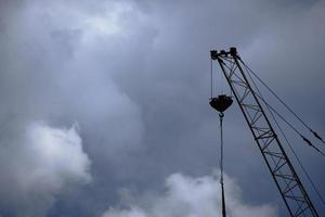 silhouette de grue de grande hauteur à flèche sur fond de nuages et de ciel dramatique. photo