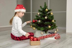 fille en bonnet de noel décore le sapin de noël, contenu de noël photo