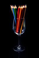 crayons multicolores dans un verre à vin et un seau. flou sélectif un groupe de crayons de couleur dans un verre à vin sur fond blanc ou noir isolé, art moderne. moderne photo
