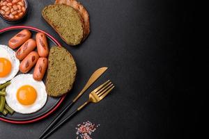 savoureux petit-déjeuner anglais composé d'œufs au plat, de haricots, d'asperges, de saucisses aux épices et d'herbes photo