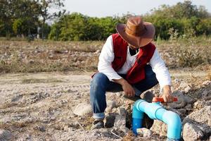 le plombier asiatique vérifie le tuyau bleu d'approvisionnement en eau dans le jardin. concevoir, installer, réparer, réparer ou entretenir un service de système d'eau utilisé pour la zone agricole. photo