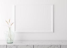 cadre photo vide sur un mur blanc dans un salon moderne. maquette d'intérieur dans un style scandinave minimaliste. espace libre pour votre image. console en marbre et herbe séchée dans un vase en verre. rendu 3d.