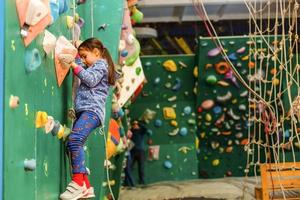 petite fille escaladant un mur de roche à l'intérieur photo