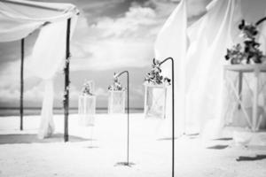 concept de mariage de destination de lune de miel artistique noir et blanc. cérémonie de mariage romantique sur la plage. installation de mariage sur la plage photo