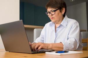 femme aînée sérieuse se réveillant sur un ordinateur portable à la maison. femme d'affaires. concept de travail à distance photo