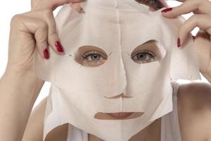 soins du visage et soins esthétiques. femme avec un masque hydratant en feuille sur son visage isolé sur fond blanc photo