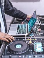 dj joue en direct et mixe de la musique sur un ordinateur portable. disque jokey mains sur un ordinateur portable au club.