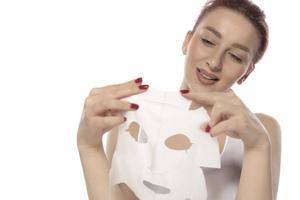 soins du visage et soins esthétiques. femme avec un masque hydratant en feuille sur son visage isolé sur fond blanc photo