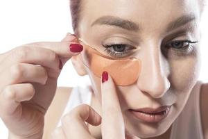 femme avec des patchs cosmétiques hydratants sur la peau sous les yeux. isolé sur fond blanc photo