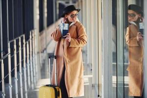 jeune passagère en vêtements chauds avec billets et bagages dans le hall de l'aéroport photo