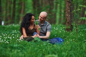 couple heureux assis sur l'herbe ensemble dans la forêt pendant la journée photo