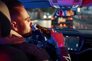 feux de police noirs et rouges. ne pas boire et conduire. vue arrière du bel homme non rasé dans des vêtements à la mode à l'intérieur de son automobile photo