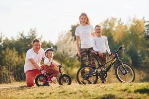 avec des vélos. famille heureuse passant le week-end ensemble à l'extérieur près de la forêt. avec fille et fils photo