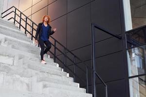 jeune femme rousse européenne a marcher dans les escaliers à l'extérieur photo