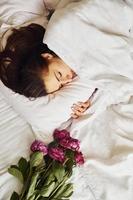 allongé sur un lit avec des fleurs. jeune femme se reposant et passant le week-end à la maison seule à la maison photo