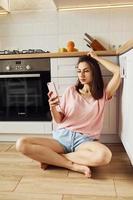 tenant le téléphone. jeune femme se reposant et passant le week-end à la maison seule à la maison photo