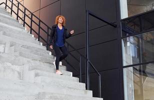 jeune femme rousse européenne a marcher dans les escaliers à l'extérieur photo