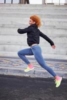 jeune femme rousse européenne en vêtements sportifs courant à l'extérieur photo