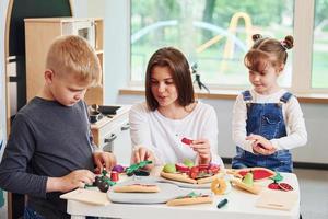 jeune femme avec petit garçon et fille jouant avec des jouets ensemble dans la cuisine photo