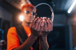 jeune artiste afro-américain debout dans un studio d'enregistrement et tenant des écouteurs photo