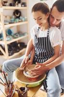 avec son petit ami ou son mari. une jeune céramiste travaille à l'intérieur avec un produit en argile fait à la main. conception de la poterie photo