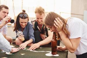 jouer au jeu de cartes. un groupe de jeunes en vêtements décontractés fait la fête ensemble sur le toit pendant la journée photo