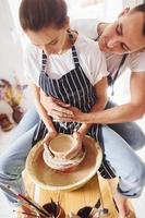 avec son petit ami ou son mari. une jeune céramiste travaille à l'intérieur avec un produit en argile fait à la main. conception de la poterie photo