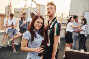 Couple heureux. un groupe de jeunes en vêtements décontractés fait la fête ensemble sur le toit pendant la journée photo