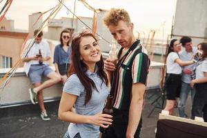 Couple heureux. un groupe de jeunes en vêtements décontractés fait la fête ensemble sur le toit pendant la journée photo