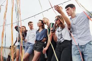 appuyé sur le bord du toit avec décore. un groupe de jeunes en vêtements décontractés fait la fête ensemble pendant la journée photo