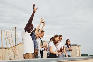 lieu décoré. temps nuageux. un groupe de jeunes en vêtements décontractés fait la fête ensemble sur le toit pendant la journée photo