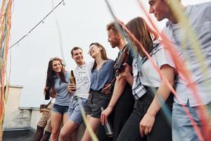 appuyé sur le bord du toit avec décore. un groupe de jeunes en vêtements décontractés fait la fête ensemble pendant la journée photo