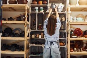 jeune femme céramiste à l'intérieur tenant un produit en argile fait main. conception de la poterie photo