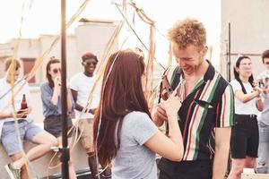 Couple heureux. un groupe de jeunes en vêtements décontractés fait la fête ensemble sur le toit pendant la journée photo