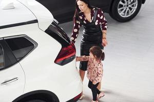 mère avec sa fille marchant ensemble près de l'intérieur de l'automobile moderne photo