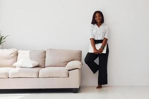 jeune femme afro-américaine en vêtements formels debout avec un ordinateur portable dans les mains à l'intérieur photo