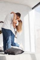 debout et embrassant sur le lit. jeune couple charmant ensemble à la maison passer le week-end et les vacances ensemble photo