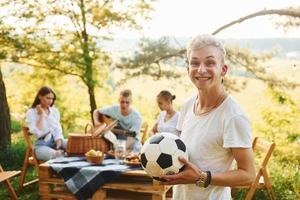 homme tenant un ballon de football. un groupe de jeunes passe des vacances à l'extérieur dans la forêt. conception de week-end et d'amitié photo