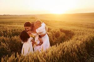 joyeuse famille de mère, petit fils et fille passant du temps libre sur le terrain aux beaux jours de l'été photo