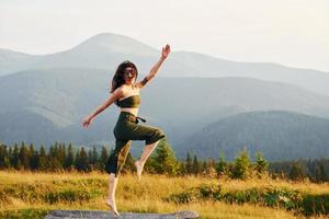 femme sportive aime faire du yoga. majestueuses montagnes des carpates. beau paysage de nature intacte photo