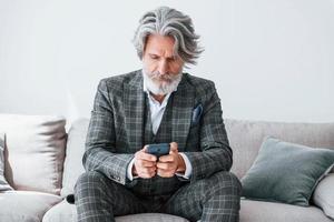 dans un appartement avec des vêtements élégants. homme moderne et élégant aux cheveux gris et à la barbe à l'intérieur photo