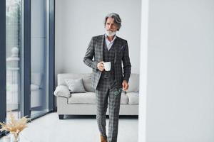 debout dans la chambre. homme moderne et élégant aux cheveux gris et à la barbe à l'intérieur photo