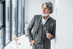 debout dans la chambre. homme moderne et élégant aux cheveux gris et à la barbe à l'intérieur photo